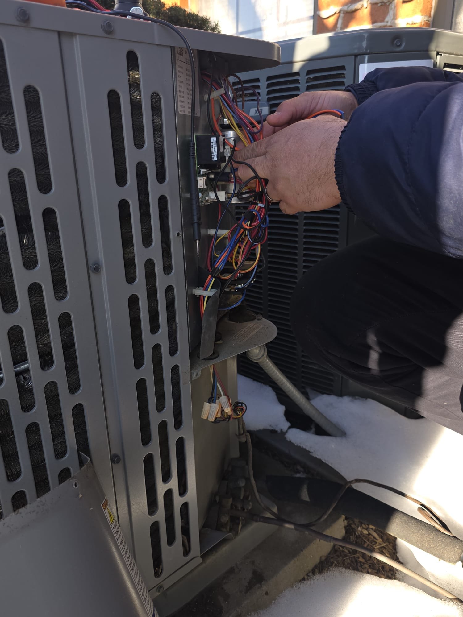 Technician servicing a condenser in the snow