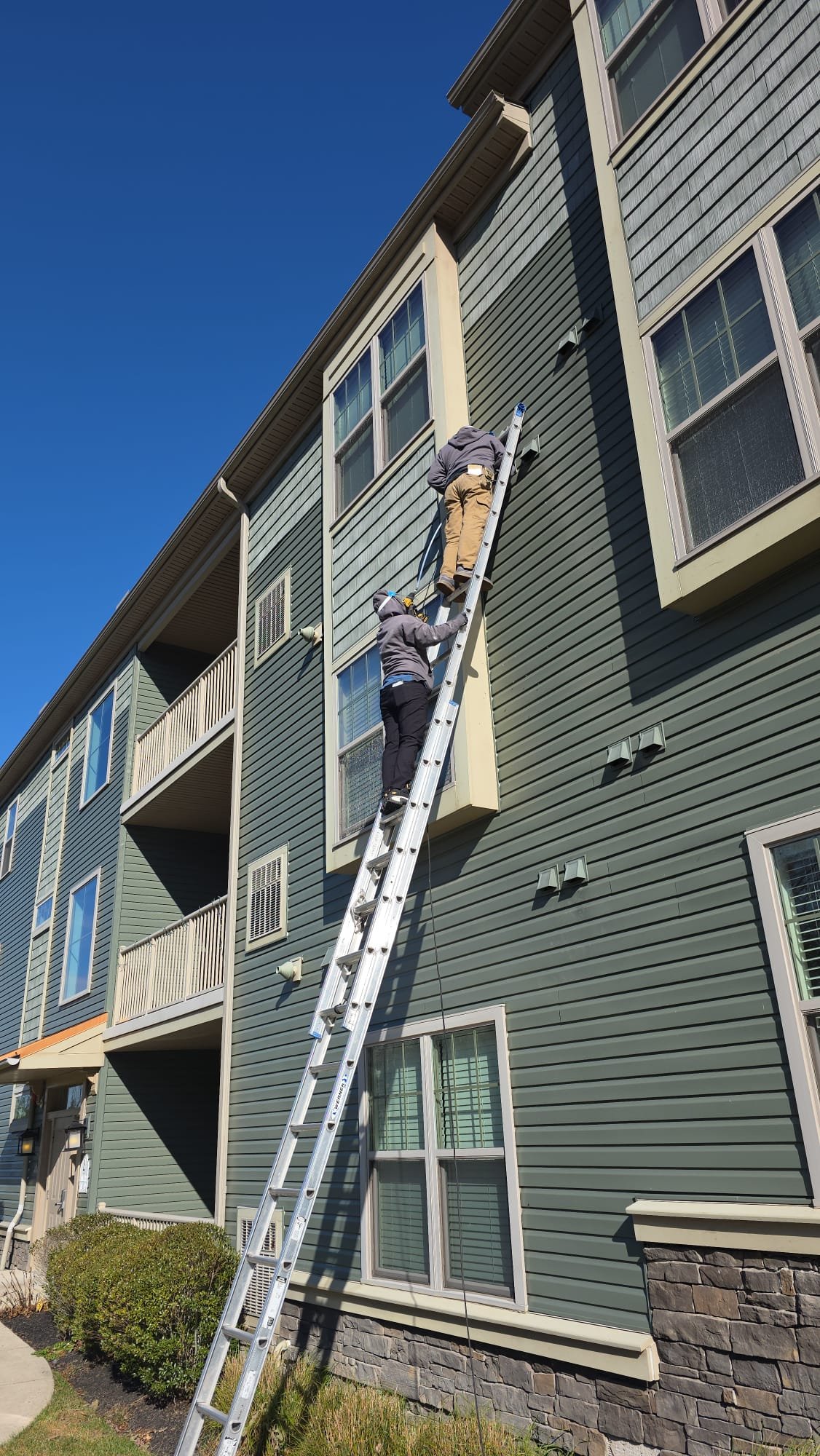 Technicians servicing exterior dryer vents on a condominium building