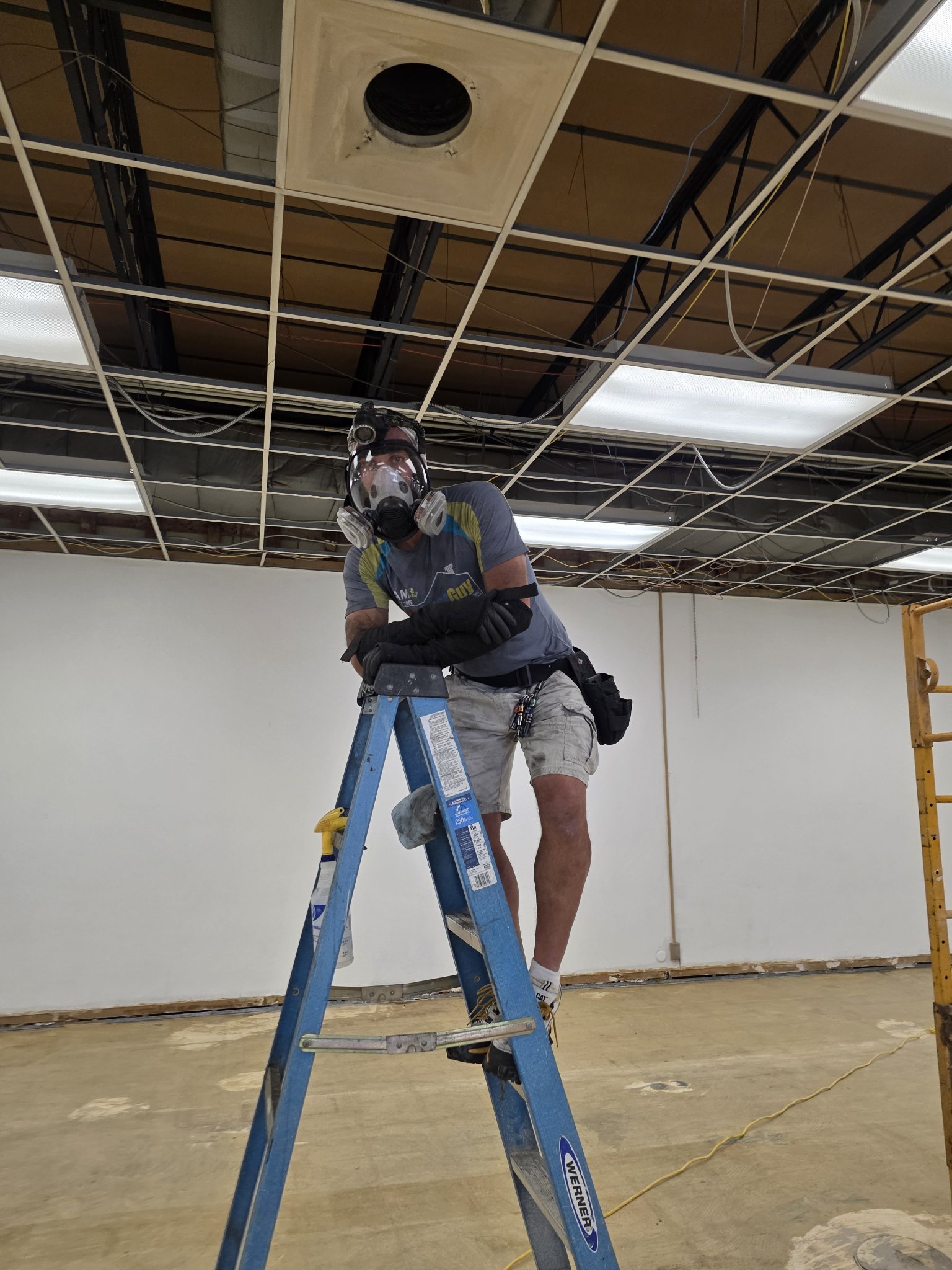 Technician On A Ladder Under Commercial Ceiling Ductwork