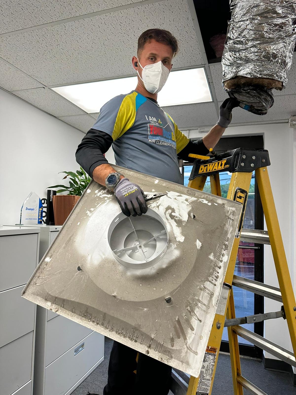 Technician Holding A Dirty Ceiling Vent Cover During Air Duct Cleaning
