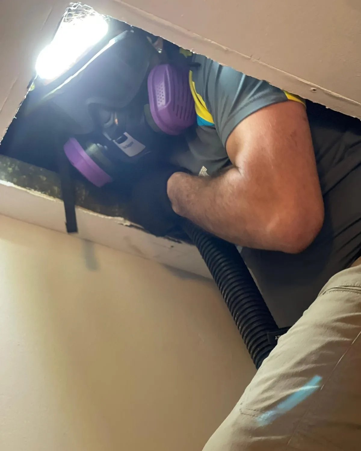 Technician inside ductwork with vacuum hose during cleaning