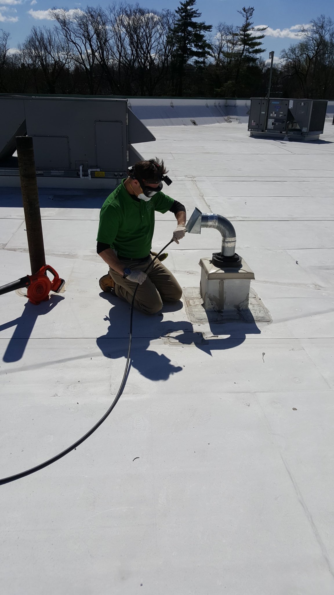 Technician Cleaning A Rooftop Dryer Vent At A Salon